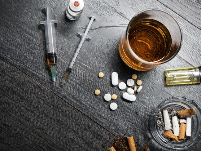 Alcohol or whiskey in a glass, drugs, syringe, cigarettes on a black wood background. Concept of bad habits