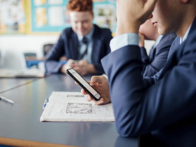 Bored male student using phone during a class.