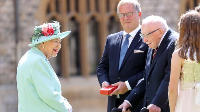 Queen Elizabeth II talks to 100-year-old veteran Captain Tom Moore and his family during an investiture to confer the Honour of Knighthood upon him at Windsor Castle. Picture: AFP.