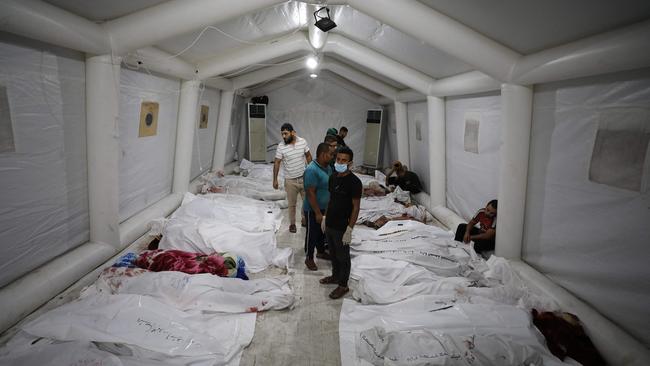 People stand over bodies of Palestinians killed in air strikes on the Ahli Arab hospital in central Gaza. Picture: AFP