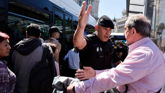 A Spanish policeman tries to keep people calm as they queue to catch a bus in Madrid during a massive power cut affecting the entire Iberian Peninsula and the south of France. Picture: Oscar del Pozo/AFP