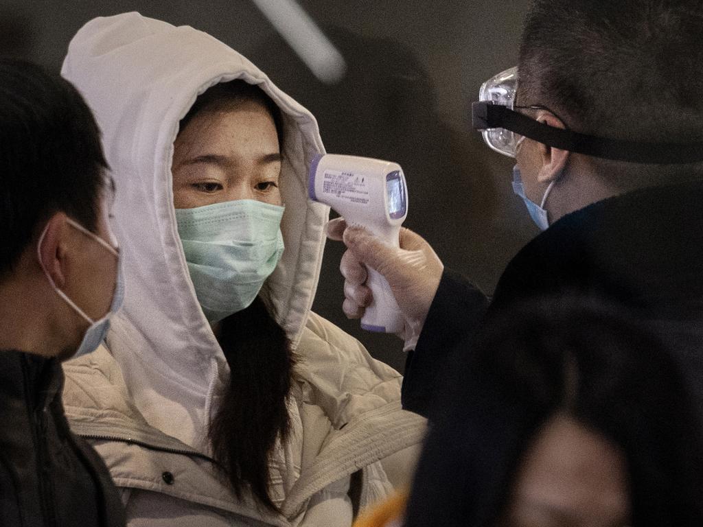 A Chinese passenger that just arrived on the last bullet train from Wuhan to Beijing is checked for a fever by a health worker at a Beijing railway station. Picture: Photo by Kevin Frayer/Getty Images.