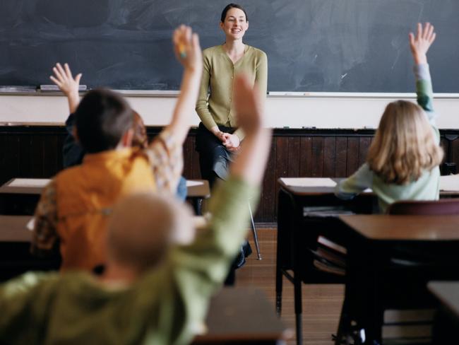 Generic pic of a teacher standing at the blackboard while talking to students in a classroom.