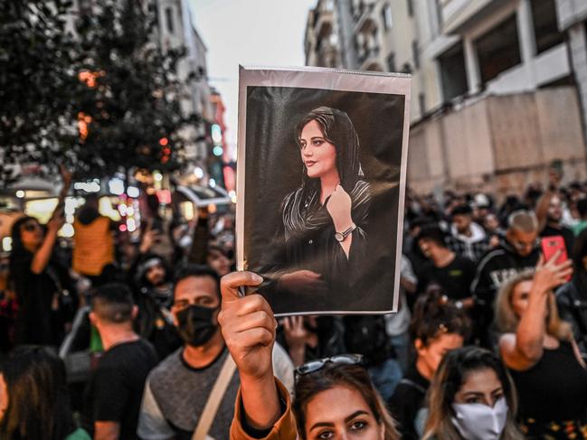 A protester holds a portrait of Mahsa Amini  during a demonstration in support of Amini, a young Iranian woman who died after being arrested in Tehran by the Islamic Republic's morality police, on Istiklal avenue in Istanbul on September 20, 2022. - Amini, 22, was on a visit with her family to the Iranian capital when she was detained on September 13 by the police unit responsible for enforcing Iran's strict dress code for women, including the wearing of the headscarf in public. She was declared dead on September 16 by state television after having spent three days in a coma. (Photo by Ozan KOSE / AFP)
