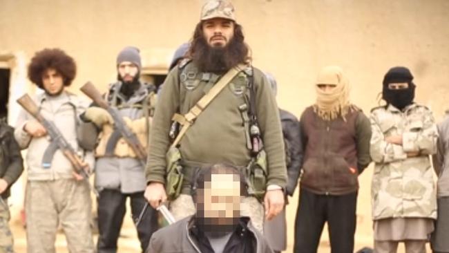 An Islamic State fighter, believed to be Khaled Sharrouf, shown in a propaganda video executing a prisoner. Mohamed Elomar behind him on the left. Source: Supplied