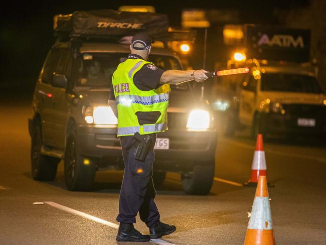 An officer signals to a motorist at the checkpoint early on Thursday morning. Picture: Glenn Hunt