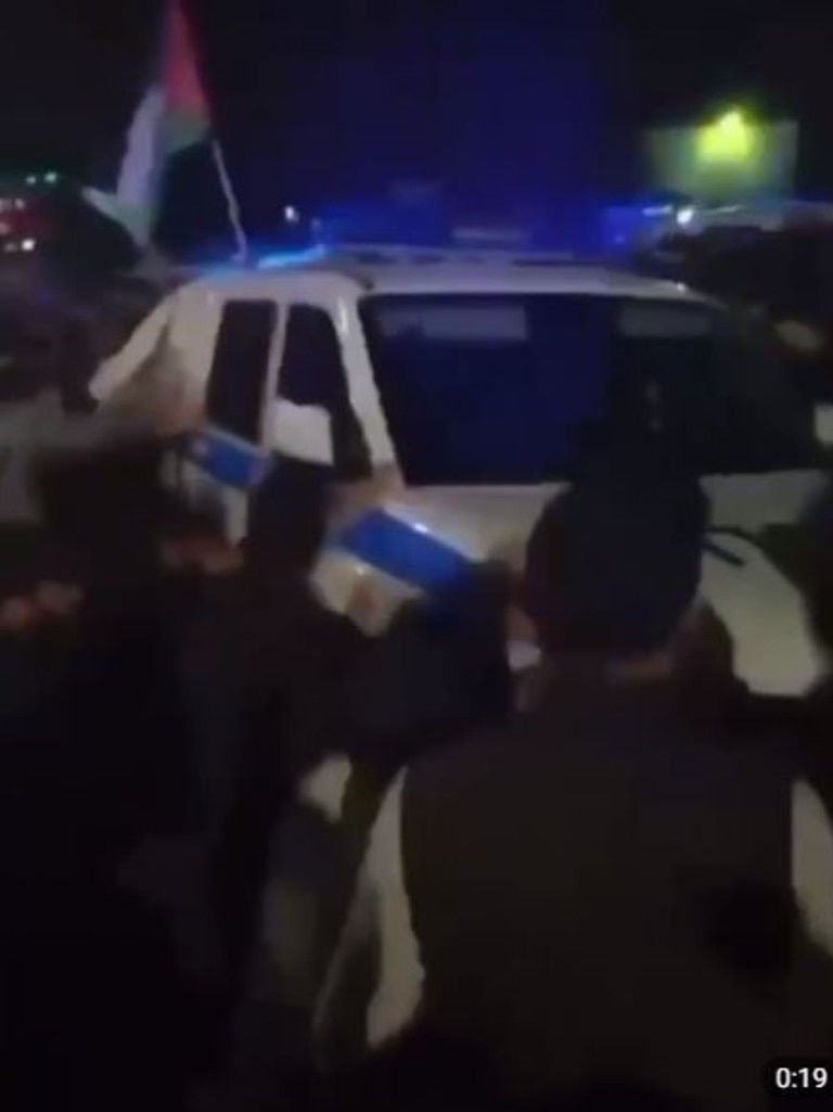 A group of men surround a police car.