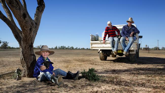 Farmhand boy Jandre Mostert, 6, cuddles a lamb on Meredith and Tony Thompson's farm in Bourke.