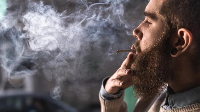 Close up of hipster man smoking weed cigarette.