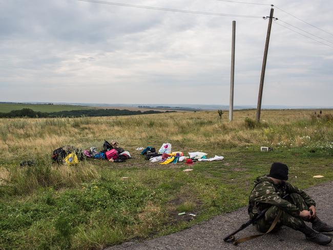 Horror scene ... A pro-Russia separatist fighter sits near personal luggage of passengers from the downed plane MH17.