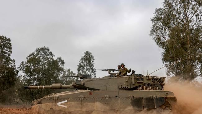 An Israeli military tank rolls near the border with the Gaza Strip on December 5, 2023, amid continuing battles between Israel and the militant group Hamas. Israel pressed on with its expanded ground operation against Hamas in the Gaza Strip, following the expiry of a seven-day truce on Friday, after which fighting resumed. Hamas militants from Gaza launched an unprecedented attack on southern Israel on October 7, killing about 1,200 people, mostly civilians, and taking around 240 hostages, according to Israeli officials. (Photo by Menahem KAHANA / AFP)