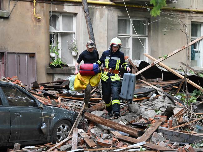 A rescuer helps a local resident to carry his belongings out from a five-storey residential building partially destroyed after drones attacks killed two and wounded 19 in eastern Ukrainian city of Sumy on July 3, 2023, the regional administration said. Picture: SERGEY BOBOK / AFP