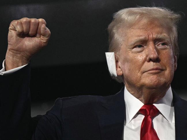 Former US President and 2024 Republican presidential candidate Donald Trump, who has a bandage on his ear after being wounded in an assassination attempt, raises a fist as he arrives during the first day of the 2024 Republican National Convention. Picture: AFP)