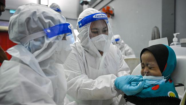 A medical worker wearing a protective suit conducts a test on a child at a free Covid-19 coronavirus testing site. Picture: AFP