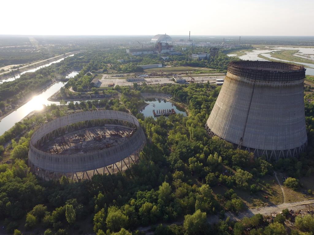 In this aerial view abandoned, partially-completed cooling towers stand at the Chernobyl nuclear power plant as the new, giant enclosure that covers devastated reactor number four stands behind in 2017. Picture: Getty