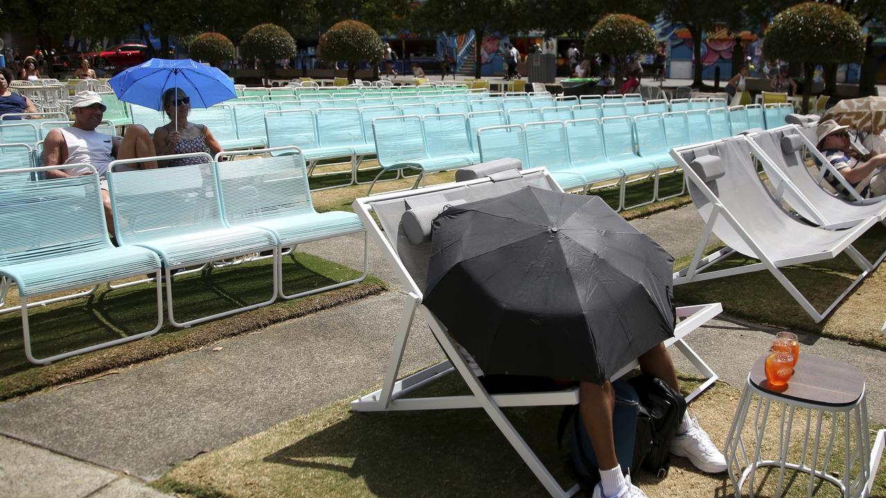 Spectators protect themselves from the heat with umbrellas as they watch tennis on a large video screen in Garden Square at the Australian Open. Picture: Aaron Favila/AP
