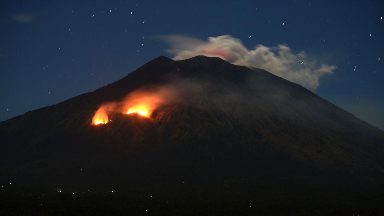 Trees burn on the slopes of Mount Agung as bright orange lava cascades from its summit. Picture: AFP PHOTO / SONNY TUMBELAKA