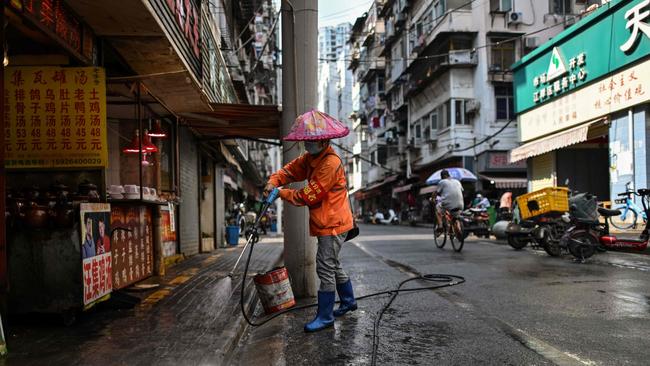 A worker cleans a street outside a market in Wuhan on Friday. Picture: AFP