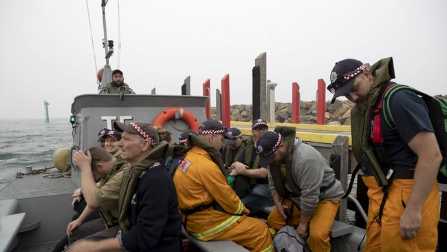 Members of the Country Fire Association board a landing craft at Mallacoota as they prepare for evacuation onboard HMAS Choules during last summer’s bushfire emergency.