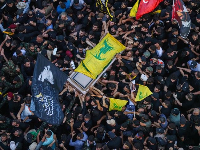 People wave flags as they accompany the casket of slain top Hezbollah commander Fuad Shukr, during his funeral procession in Beirut's southern suburbs. Picture: AFP