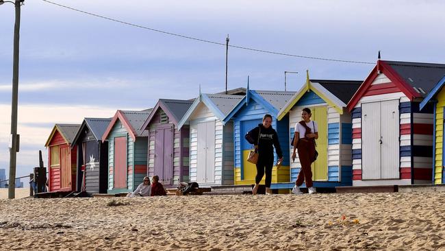 People enjoy a midwinter walk in front of the Brighton bathing boxes this week. Picture: William West