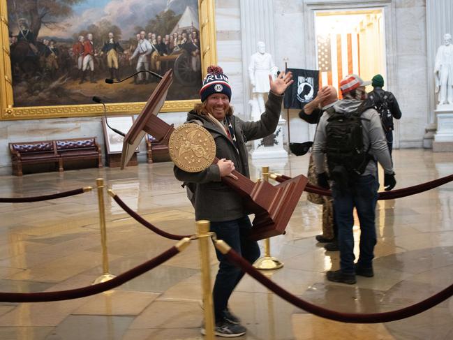 WASHINGTON, DC - JANUARY 06: A pro-Trump protester carries the lectern of U.S. Speaker of the House Nancy Pelosi through the Roturnda of the U.S. Capitol Building after a pro-Trump mob stormed the building on January 06, 2021 in Washington, DC. Congress held a joint session today to ratify President-elect Joe Biden's 306-232 Electoral College win over President Donald Trump. A group of Republican senators said they would reject the Electoral College votes of several states unless Congress appointed a commission to audit the election results.   Win McNamee/Getty Images/AFP == FOR NEWSPAPERS, INTERNET, TELCOS & TELEVISION USE ONLY ==