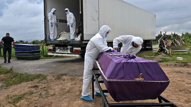 Workers remove body bags of 12 unidentified civilians from the back of a morgue container to be laid in coffins ready for burial at a cemetery in the city of Bucha in Ukraine this month. Picture: AFP