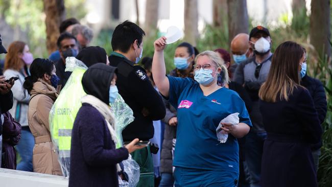 NSW Health staff member is seen handing out masks at as long queues of people are seen lining up to get the Covid-19 Vaccine at the Olympic Park Vaccination Hub in Sydney Australia. Picture: NCA NewsWire / Gaye Gerard