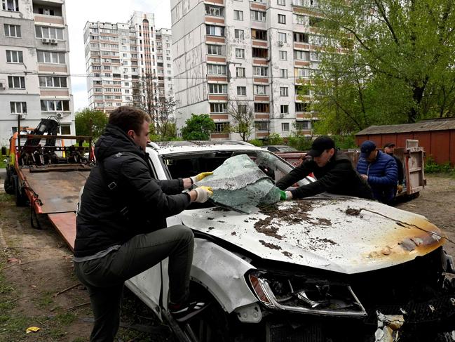 Workers load a destroyed car on the lorry after the remains of a shot down Russian drone exploded near residential buildings in Kyiv. Picture: AFP