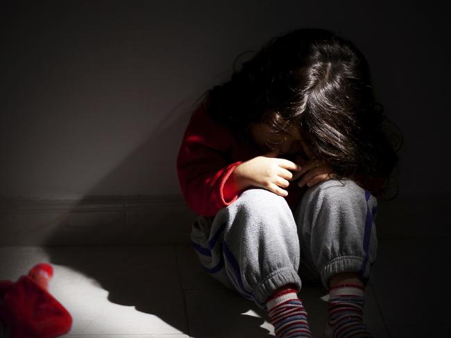 young girl sitting down alone in the dark. iStock image