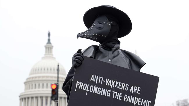 A man holds a sign and dresses as a plague doctor to encourage people to be vaccinated and prevent prolonging the COVID-19 pandemic on Capitol Hill in Washington, DC.