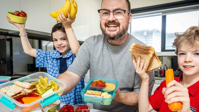 Doing it together: Cameron Williams helps his kids Dot, 7, and Crosby, 9, pack their lunch boxes. Picture: Jake Nowakowski