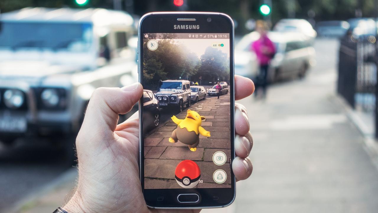 AUGMENTED REALITY Edinburgh, UK - July 18, 2016: Closeup of a man holding a Samsung S6 smartphone, playing Pokemon Go with the game's augmented reality superimposing a character onto the pavement surface, as a person approaches in the distance.  Image: iStock For Study Options 2017 feature