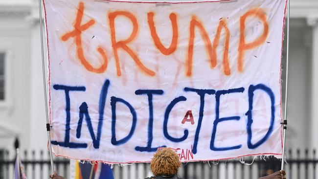 A woman celebrating the indictment of former US president Donald Trump holds a banner in front of the White House in Washington, DC, on June 9, 2023. (Photo by Mandel NGAN / AFP)