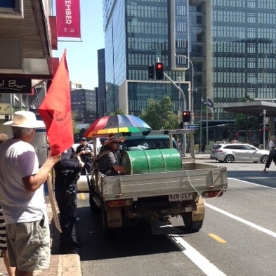 A protester has been put in the back of a ute while still attached to a barrel. Picture: Kay Dibben