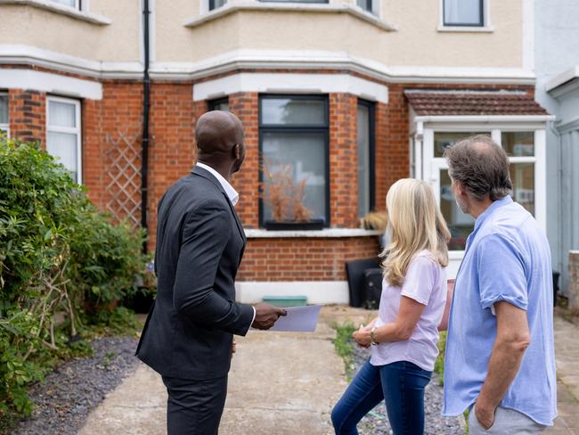 Overconfidence.  Couple looking at the front view of a house for sale with a real estate agent - home ownership concepts