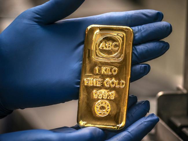 A worker displays a one kilogram gold bullion bar at the ABC Refinery in Sydney on August 5, 2020. - Gold prices hit 2,000 USD an ounce on markets for the first time on August 4, the latest surge in a commodity seen as a refuge amid economic uncertainty. (Photo by DAVID GRAY / AFP)