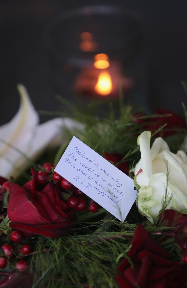 A candle burns next to flowers at the entrance to Schiphol Airport.