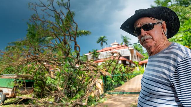 Wayne Patten, of Fannie Bay, surveys the damage to his driveway and car after the milkwood tree that had stood in his front yard since before Cyclone Tracy fell when a squall hit Darwin. Picture: Che Chorley