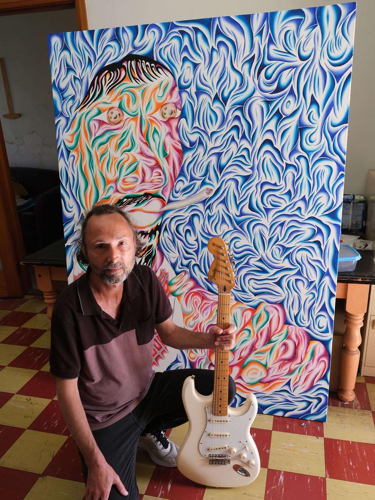 Steve Horvath, who paints under the moniker Jimi Hendrix, pictured in front of an abstract portrait titled “Not the person you think you are”, holding a Jimi Hendrix replica Fender guitar. Picture: Mark Wilson