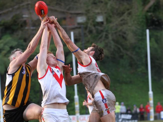 Olinda Ferny Creek's Lachie Taylor (middle) reaches high.