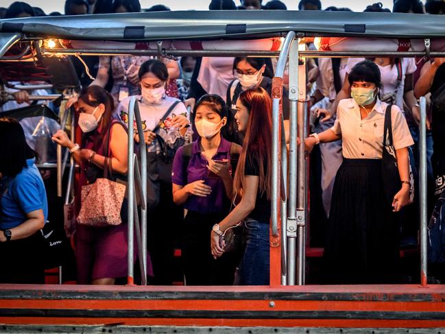 Commuters with protective face masks board a canal boat at Pratunam Pier in Bangkok. Picture: AFP