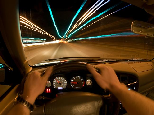 Night Speeding. Motorist behind wheel of car.