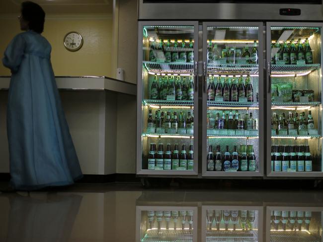 A factory guide stands next to a refrigerator containing different types of beer produced at the Taedonggang Brewery in Pyongyang. Picture: Wong Maye-E/AP