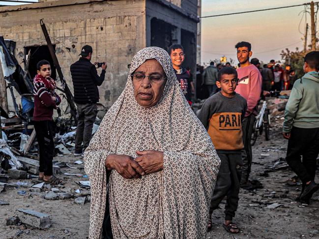 An elderly woman walks past youths near buildings heavily damaged by Israeli bombardment in Rafah. Picture: AFP