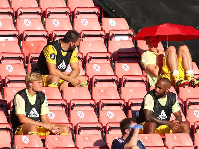 Mesut Ozil sits in the stands under an umbrella during a match last season. (Photo by Catherine Ivill/Getty Images)