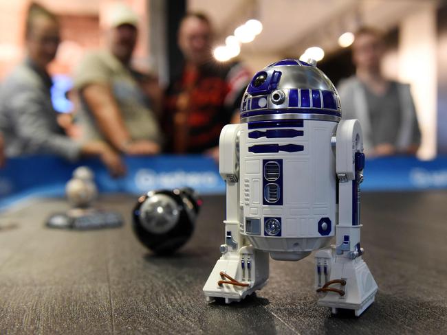 Visitors look at remotely controlled roboters from the Star Wars movies at the booth of Sphero at the IFA Consumer Electronics Fair in Berlin on September 2, 2017. The fair is open for the public from September 1 to 6, 2017. / AFP PHOTO / dpa / Maurizio Gambarini / Germany OUT