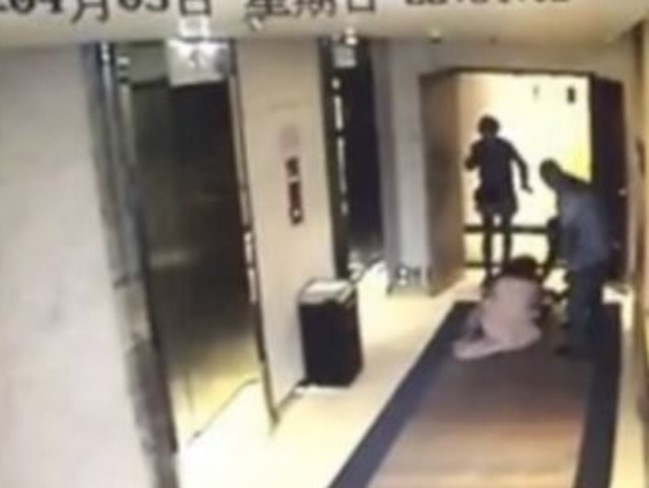 The woman is dragged to the ground by the man as a bystanders watches on.