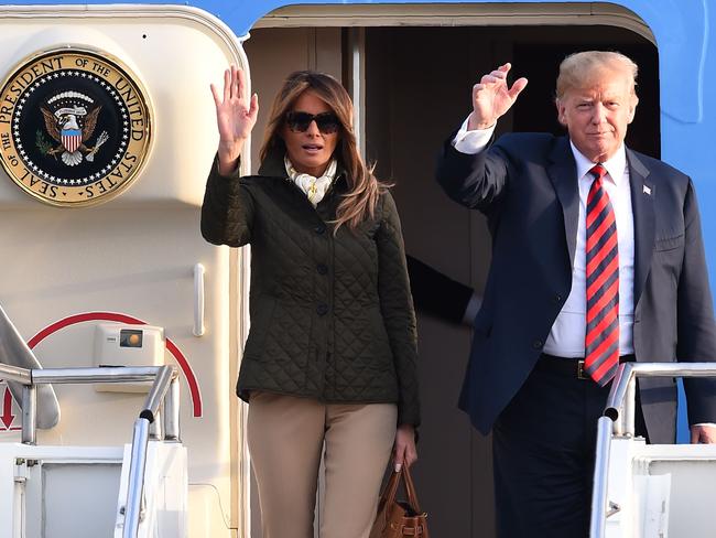 US President Donald Trump waves as he disembarks Air Force One with US First Lady Melania Trump.