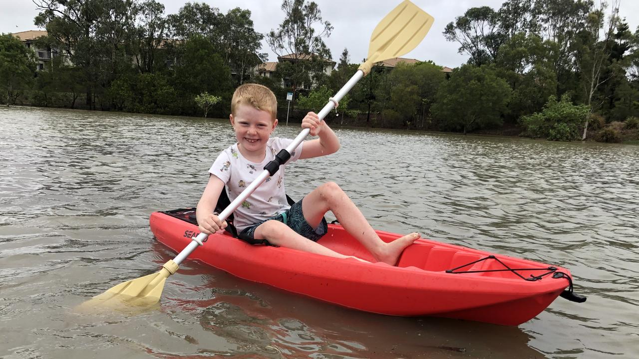 Flynn Spink, 6, goes for a kayak paddle in a flooded park at Pacific Pines. Photo: Jeremy Pierce